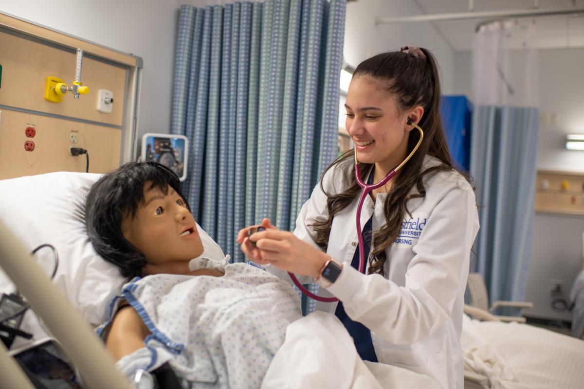 Nursing student practicing on a mannequin in a lab.