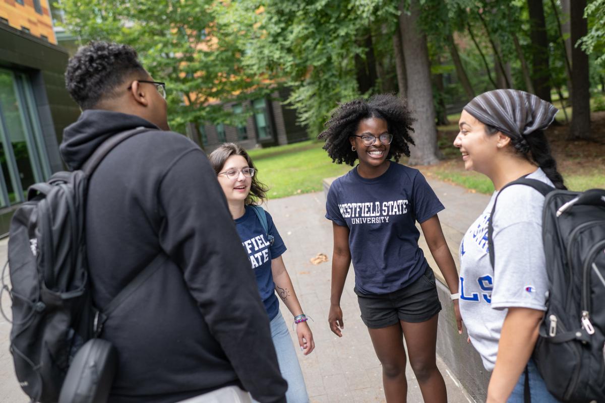 Students standing outside dorms, smiling while wearing Westfield State University t-shirts.