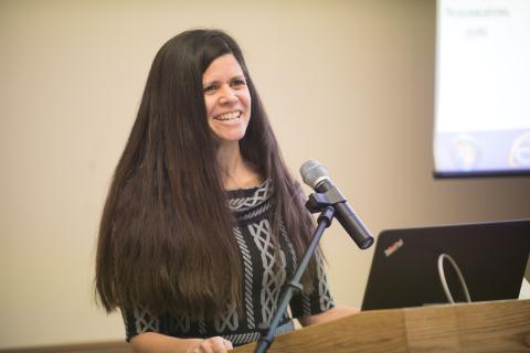 Dr. Catherine Savini stands at a podium and speaks into a microphone