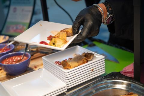 A close-up shot of Chef Ming from the Iron Chef at the University's annual fall food show. There's a stack of white, square plates, and homemade bings on them, which are Chinese streetfood crepes.