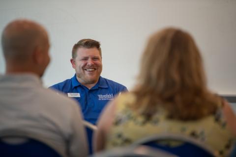 Director of Student Activities, Involvement, and Leadership, Matt Dellea. He is in a blue polo shirt and speaking to parents for New Student Orientation Day.