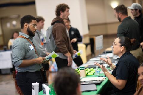 Students talk to people at tables