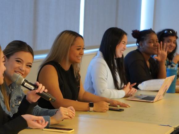 A group of students gathered at a table speaking.