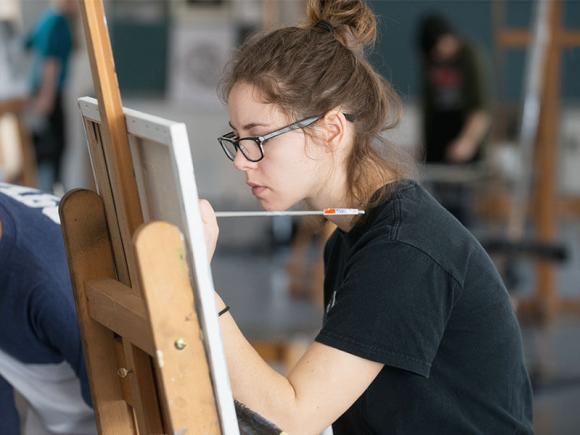 A student works on their painting while in class.