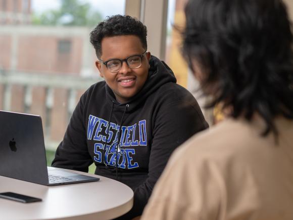 Two students talking, one wearing a WSU sweatshirt, engaging in a friendly conversation.