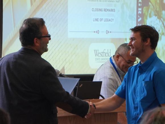 Student and faculty member shaking hands at a campus event.