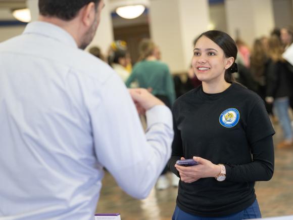 Nursing student smiling while talking to an employer at a healthcare career fair.