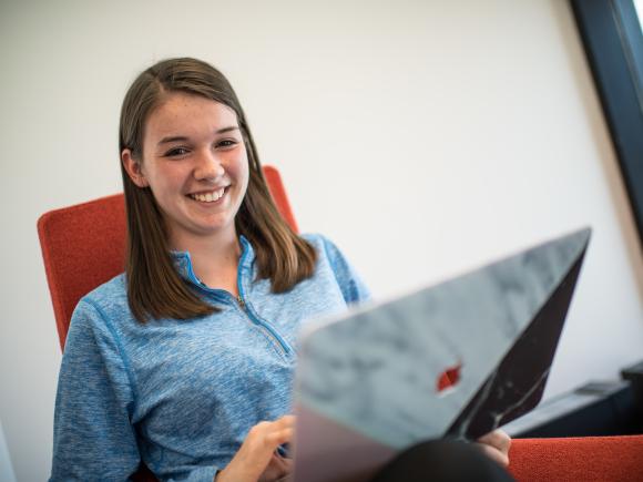 Student smiling while working on a laptop.