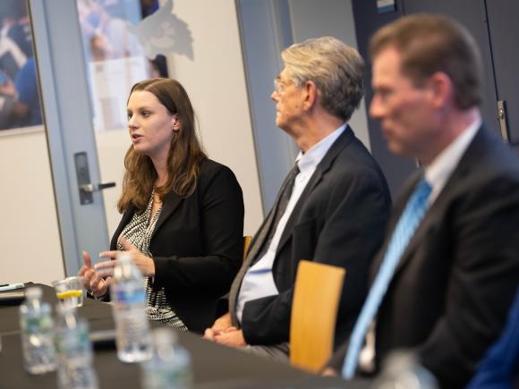 A female legal professional speaks and gestures during Westfield State University's Pursuing a Career in Law panel discussion, seated alongside fellow panelists.