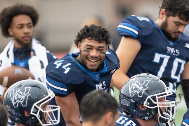 Westfield State football player smiles at his teammates on the sidelines during a game