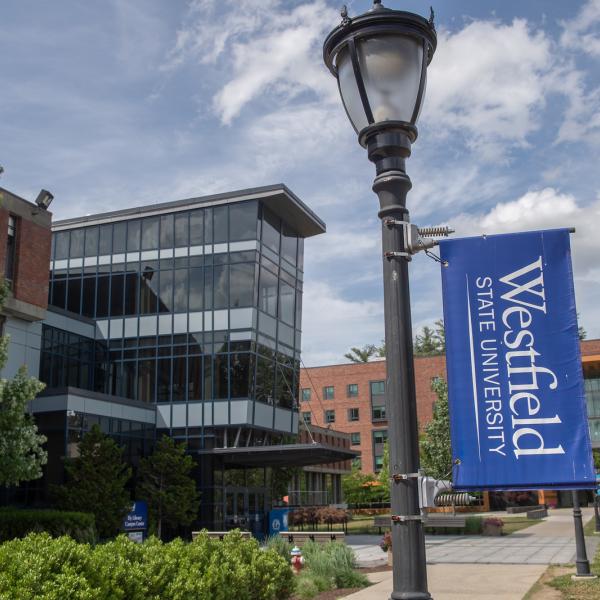 Exterior of Ely Campus Center with a Westfield State University flag on a nearby light post.