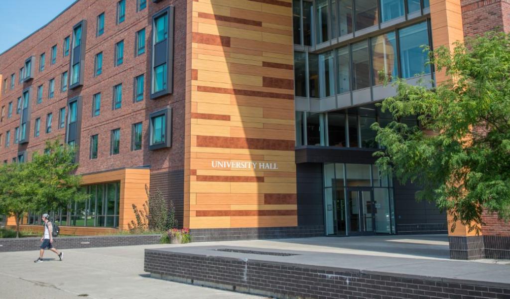 A wide view of the entrance to University Hall—a large five-story building with lots of windows and an orange facade.