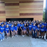 A photo of the Honors Program Students during their two-day orientation. They're standing together beside University Hall in blue shirts.