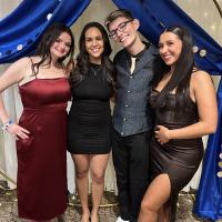 Group of students stand in front of formal backdrop