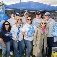 Alumni stand in front of decorated Homecoming tent